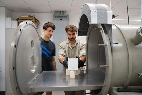 two men standing by research equipment